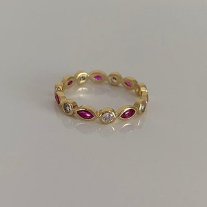 May include: A gold band ring with alternating marquise-shaped pink gemstones and round white gemstones.