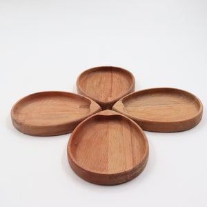 May include: Four wooden bowls in the shape of a flower. The bowls are light brown and have a smooth finish.