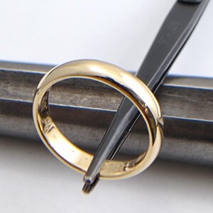 May include: A gold wedding band being sized with a pair of pliers.