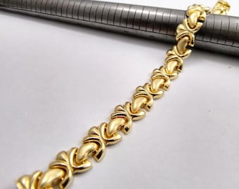 May include: A gold-tone bracelet with a linked chain design. Each link is shaped like a heart with a rounded edge.