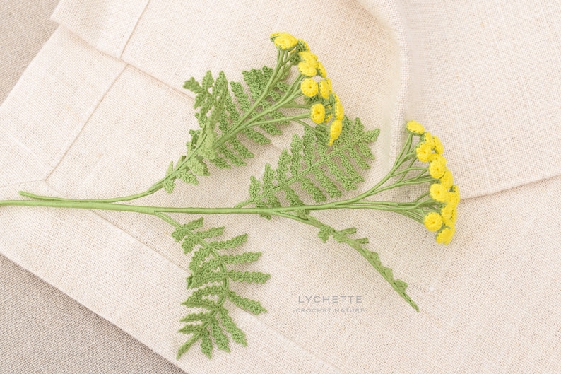May include: A crocheted sprig of yellow flowers with green leaves on a beige linen background. The text "LYCHETTE CROCHET NATURE" is visible in the bottom right corner of the image.
