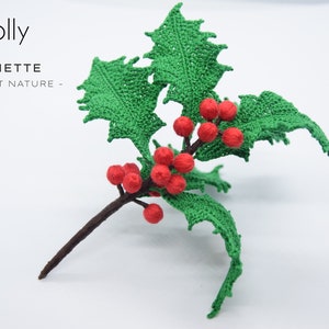 May include: A crocheted holly sprig with green leaves and red berries. The sprig is on a white background. The text "Holly" and "LYCHETTE - CROCHET NATURE -" is visible in the image.