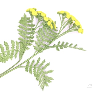 May include: A crocheted sprig of yellow tansy flowers with green leaves.