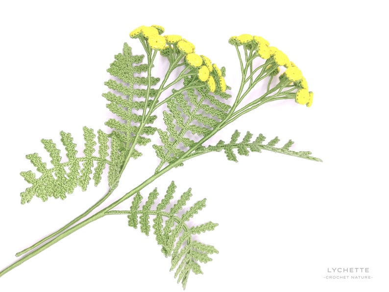 May include: A crocheted sprig of yellow tansy flowers with green leaves.