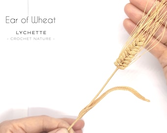 Puede incluir: Una espiga de trigo tejida a crochet con un tallo largo, el trigo es de color marrón claro y el tallo es de color beige claro. El texto "Ear of Wheat" y "LYCHETTE - CROCHET NATURE -" es visible en la imagen.