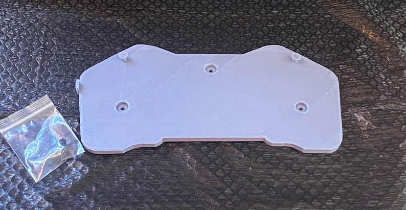 May include: A light gray plastic 3D printed part with five holes for screws. A small bag of screws is included.