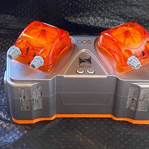 May include: A gray and orange Neptune Systems DOS pump with two orange dosing heads. The pump has a label that says "DOS" and "Neptune Systems".