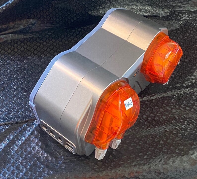 May include: A silver and orange dual-head dosing pump with the word "MAG" on one of the orange heads.
