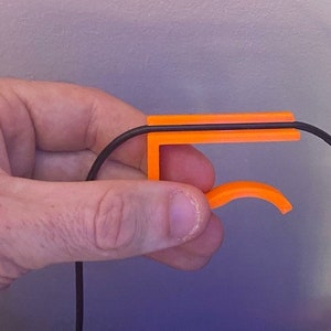 May include: Orange plastic cable organizer with a black cable running through it.