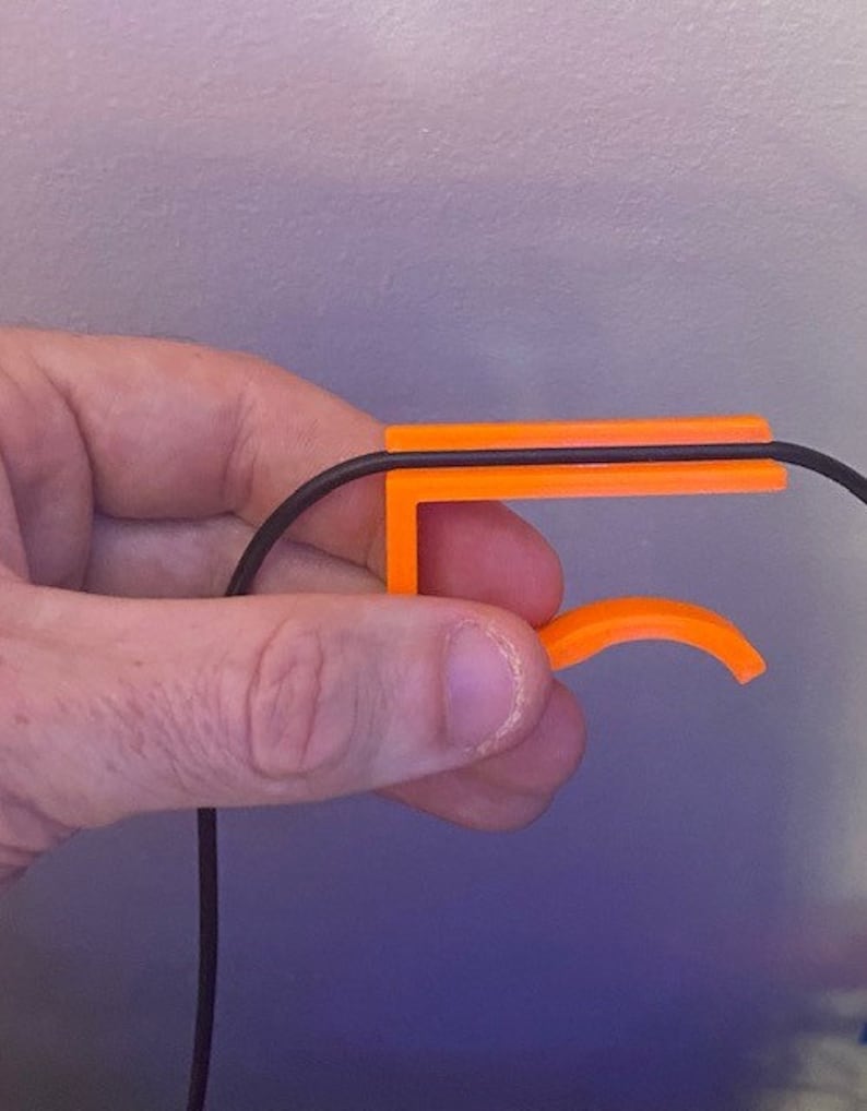 May include: Orange plastic cable organizer with a black cable running through it.