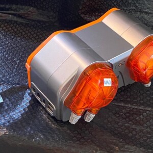May include: A silver and orange dual-channel dosing pump with two clear orange dosing heads. The pump has a label that says "DOS" and one of the dosing heads has a label that says "MAG".
