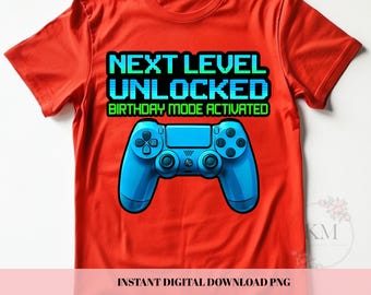 Könnte beinhalten: Rotes T-Shirt mit blauem Videospiel-Controller-Design. Der Text lautet "NEXT LEVEL UNLOCKED BIRTHDAY MODE ACTIVATED" in einer pixeligen Schriftart. Der Controller ist blau.