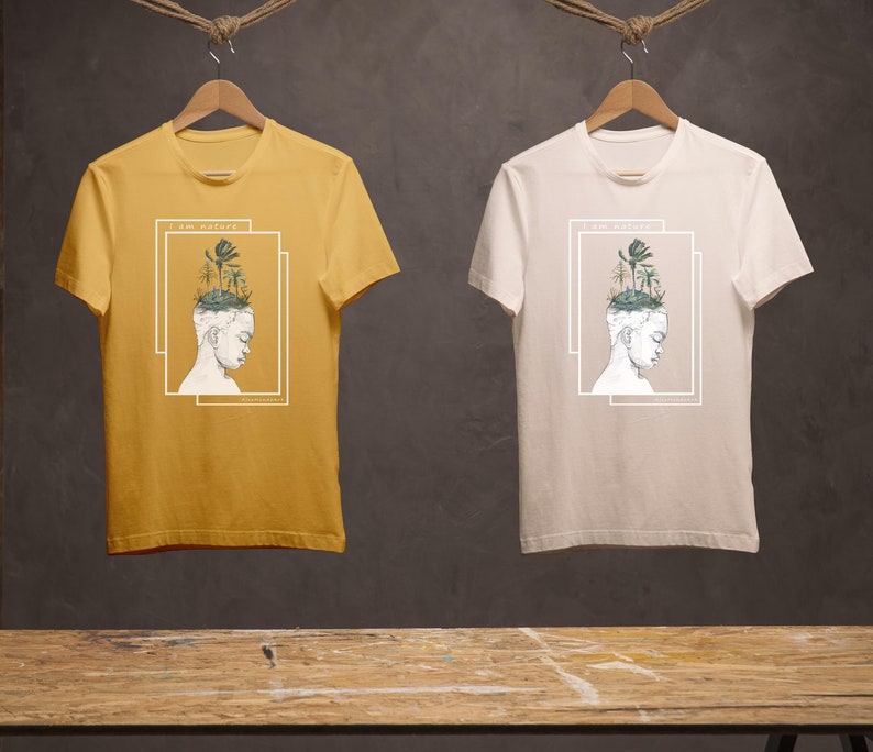 Puede incluir: Dos camisetas con un dise&ntilde;o gr&aacute;fico de una persona con un bosque creciendo de su cabeza. El texto en las camisetas dice "Soy naturaleza". Una camiseta es amarilla y la otra es blanca.