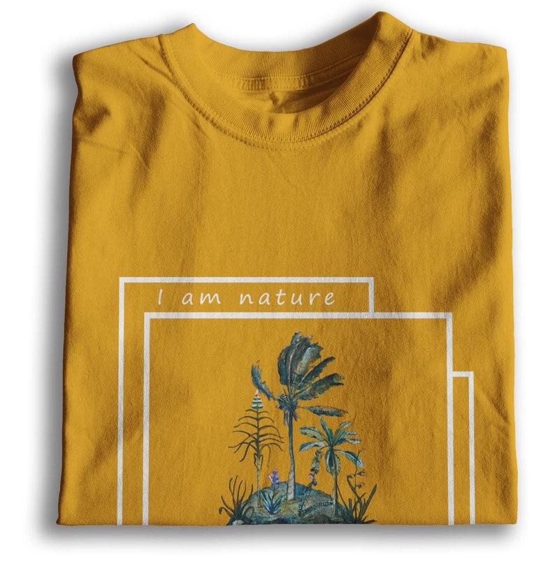 Puede incluir: Una camiseta amarilla mostaza con un estampado gr&aacute;fico blanco de una escena tropical con el texto "I am nature" en un cuadro blanco.