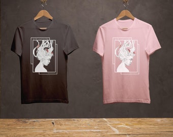 Puede incluir: Dos camisetas con un diseño gráfico de una mujer con peces en el pelo. El texto "wild curiosity" está impreso en ambas camisetas. Una camiseta es negra y la otra es rosa.