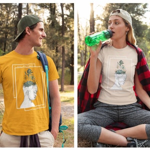 Puede incluir: Dos personas con camisetas con un gr&aacute;fico de una cabeza con plantas que crecen. El texto de la camiseta dice "Soy Naturaleza".
