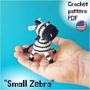 May include: Crochet pattern PDF for a small black and white zebra amigurumi toy. The toy is being held in a person's hand. The text "Small Zebra" is at the bottom of the image.