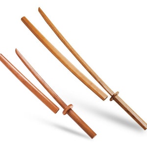 May include: Two wooden practice swords, or bokkens, are shown on a white background. One bokken is longer than the other and has a rounded tip. The shorter bokken has a handle with a circular guard.