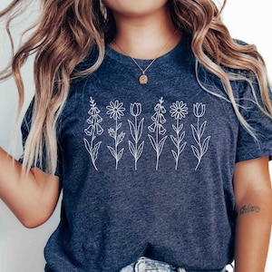May include: Navy blue t-shirt with a white floral line art design. The graphic features five different flower types in a row. The shirt is made of a soft material and is suitable for casual wear.