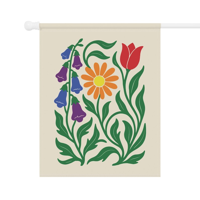 May include: A beige garden flag featuring a colorful floral design. The design includes a red tulip, an orange daisy, and blue and purple bell-shaped flowers, all with green leaves and stems. The flag is mounted on a white pole.