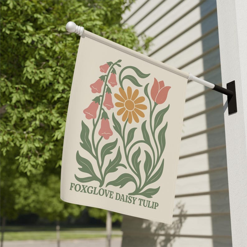 May include: A cream-colored garden flag featuring a floral design with foxgloves, a daisy, and a tulip. The flowers are in shades of peach, orange, and green. The text "FOXGLOVE DAISY TULIP" is printed at the bottom of the flag.