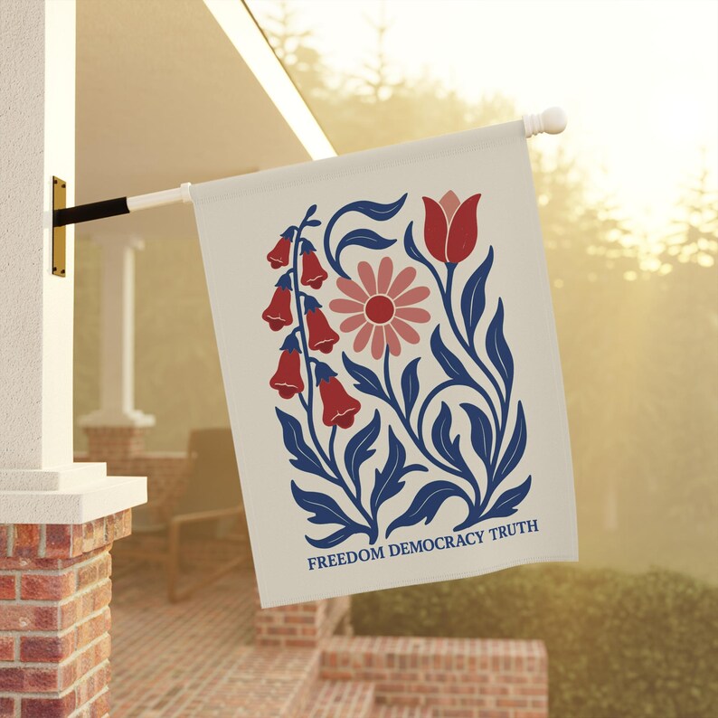 Peut inclure: Un drapeau de jardin rectangulaire blanc cass&eacute; avec une illustration botanique de fleurs rouges en forme de cloche, une marguerite rose et une tulipe rouge avec des feuilles et des tiges bleu fonc&eacute;. Le texte FREEDOM DEMOCRACY TRUTH est imprim&eacute; en bleu.