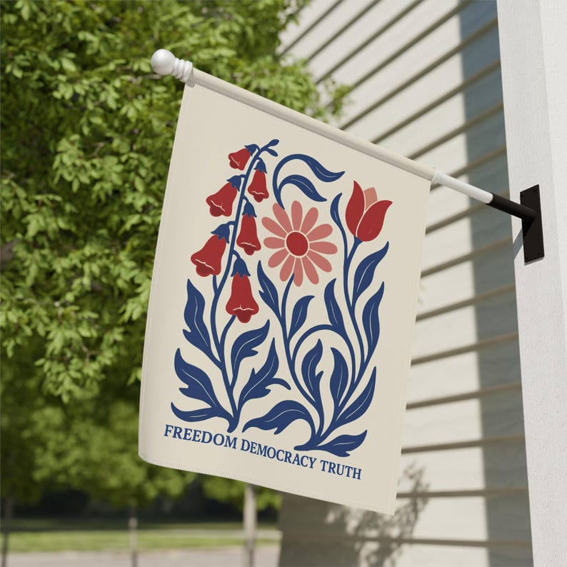 Peut inclure: Un drapeau de jardin rectangulaire blanc cass&eacute; suspendu &agrave; un m&acirc;t en m&eacute;tal noir. Le drapeau pr&eacute;sente une illustration graphique de fleurs rouges en forme de cloche, une marguerite rose et une tulipe rouge avec des feuilles bleu fonc&eacute;. Le texte FREEDOM DEMOCRACY TRUTH est imprim&eacute;.