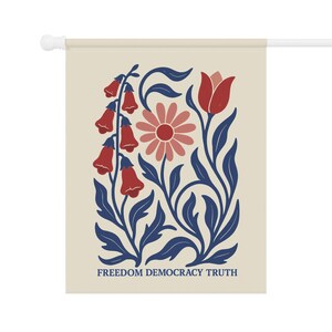Peut inclure: Un drapeau mural rectangulaire sur fond cr&egrave;me pr&eacute;sentant une illustration botanique de fleurs rouges en forme de cloche, une marguerite rose et une tulipe rouge avec des feuilles bleu fonc&eacute;. Le texte FREEDOM DEMOCRACY TRUTH est imprim&eacute; en bleu.