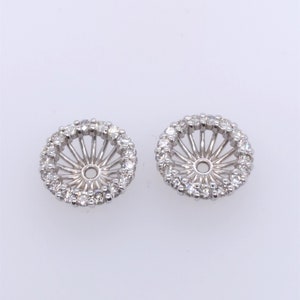 May include: A pair of silver earring settings with a round diamond halo. The settings are designed to hold a pearl or gemstone.