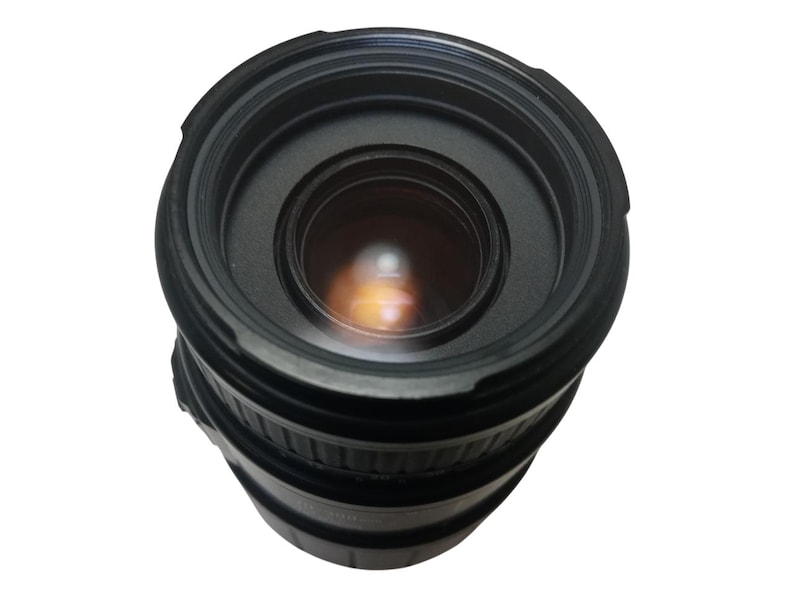 May include: A black camera lens with a wide aperture. The lens has multiple rings and a glass element that reflects light. The lens is designed for use with a digital camera.