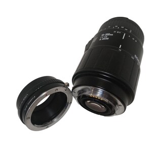 May include: Black Sigma 70-300mm f/4-5.6 DL Macro lens with a detached lens adapter. The lens has white markings and a silver ring. The adapter is black with silver accents and the text "Polar V/R".