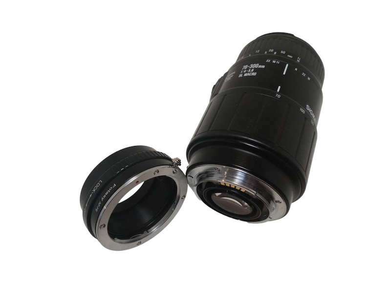 May include: Black Sigma 70-300mm f/4-5.6 DL Macro lens with a detached lens adapter. The lens has white markings and a silver ring. The adapter is black with silver accents and the text "Polar V/R".