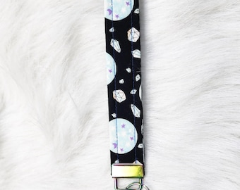 May include: Black fabric key chain with a white and blue moon and star pattern and silver and gold colored metal key ring.