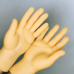 Op de afbeelding: Twee gele rubberen handen met open handpalmen en gespreide vingers.