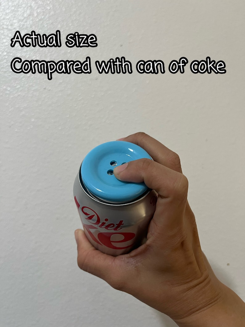 May include: A blue button-shaped lid on top of a silver can of Diet Coke. The text "Diet Coke" is visible on the can.