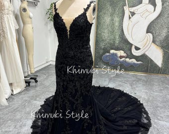 May include: A black mermaid-style gown with a lace bodice and a sheer neckline. The gown has a fitted silhouette and a flowing train. The gown is displayed on a mannequin in a shop setting.