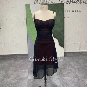 K&ouml;nnte beinhalten: Ein schwarzes und burgunderfarbenes Kleid mit einem figurbetonten Oberteil und einem flie&szlig;enden Chiffonrock. Das Kleid hat d&uuml;nne Tr&auml;ger und einen herzf&ouml;rmigen Ausschnitt.