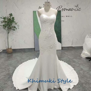 May include: A white strapless mermaid wedding dress with lace detailing and a flowing train. The dress is on a mannequin and the text "Romantic" and "Khimuki Style" is visible.