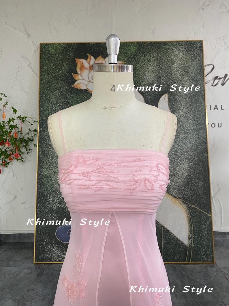 May include: A light pink strapless dress on a mannequin. The bodice features horizontal ruching and embroidered floral details. The skirt is a flowing, sheer fabric. The text "4Khimuki Style" is visible on the dress.
