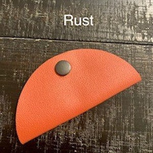 May include: A bright orange leather taco-shaped coin purse with a black snap closure.
