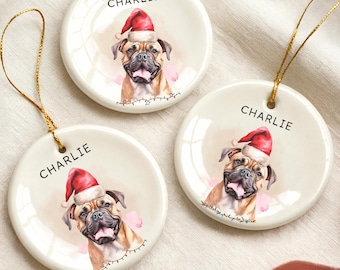 May include: Three round ceramic Christmas ornaments featuring a dog wearing a Santa hat. Each ornament has the name "Charlie" printed on it. The dog is a light brown color with a pink background and a string for hanging.