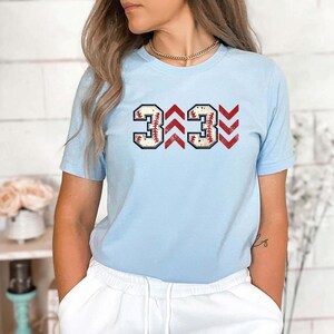 Baseball graphic shirt featuring the phrase 3 Up 3 Down displayed in bold distressed numbers with directional arrow accents; athletic-inspired typography arranged in a centered layout that reflects classic baseball scoreboard style; clean sports design created for fans players and game day wear