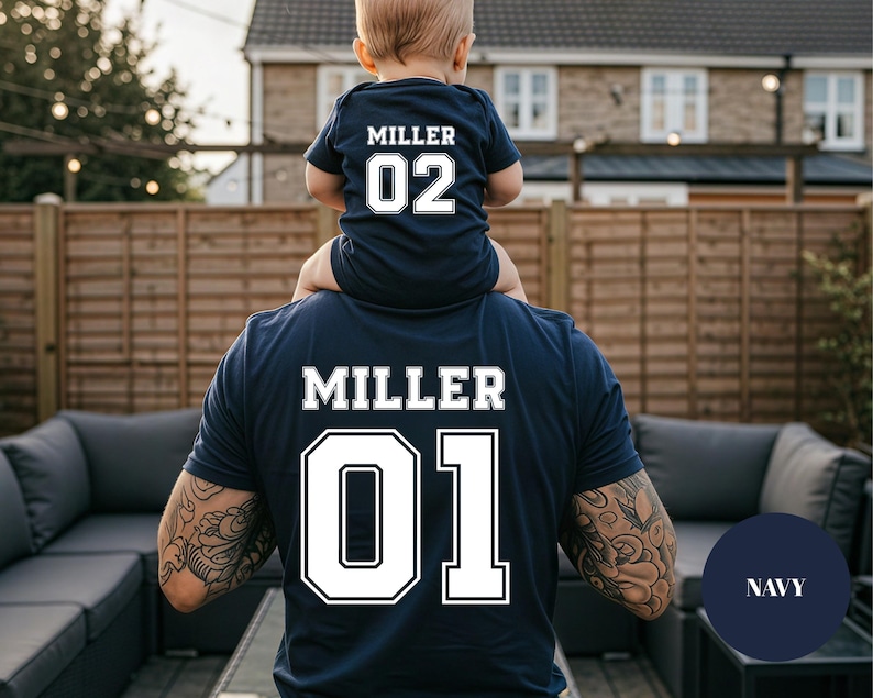May include: Navy blue matching shirts with the name "MILLER" and numbers "01" and "02" in white. The "02" shirt is a baby onesie. The "01" shirt is an adult t-shirt. The shirts are worn by a parent and child.