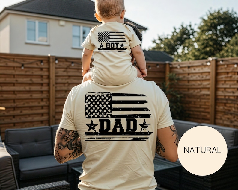 Puede incluir: Camisetas beige a juego con un dise&ntilde;o de bandera americana desgastada. La camiseta del adulto dice "DAD" y la del ni&ntilde;o "BOY". Las camisetas son de color beige claro.
