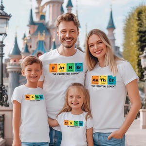 May include: A family of four wearing white t-shirts with a periodic table element design. The shirts say "Father", "Mother", "Brother", and "Sister" with the corresponding element symbols. The shirts also include the phrase "The Protective Element", "The Essential Element", "The Wild Element", and "The Vibrant Element".