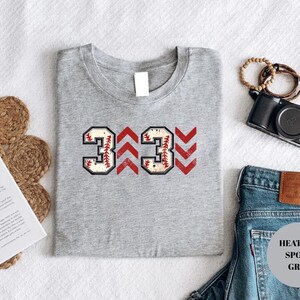 Baseball graphic shirt featuring the phrase 3 Up 3 Down displayed in bold distressed numbers with directional arrow accents; athletic-inspired typography arranged in a centered layout that reflects classic baseball scoreboard style; clean sports design created for fans players and game day wear