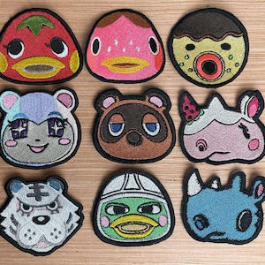 Puede incluir: Diez parches bordados con diferentes personajes de animales. Los parches son coloridos y presentan una variedad de diseños, incluyendo una fresa, un pez, un mapache, un rinoceronte, un perro, un gato y una rana.