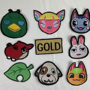 May include: Nine embroidered patches featuring various animal characters from the Animal Crossing video game series. The patches are colorful and feature characters like a green bird, a pink dog, a blue cat, and a red hippo. The patches are all surrounded by a black outline and have a white background. One patch features the word "GOLD" in black letters on a brown background.
