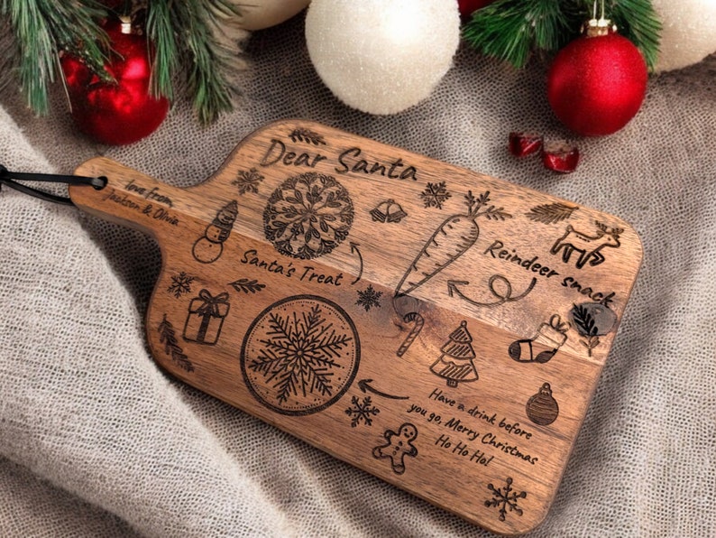 May include: Wooden Christmas serving board with engraved holiday illustrations and text. The board features a snowman, snowflake, gift, carrot, reindeer, and the words "Dear Santa," "Santa's Treat," and "Reindeer snack."