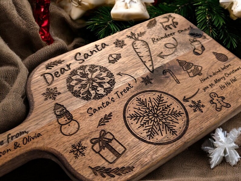 May include: A wooden serving board with engraved Christmas-themed designs. The board features text that reads "Dear Santa" and "Santa's Treat", along with illustrations of a carrot, snowflake, snowman, and gift. The board is a light brown color.